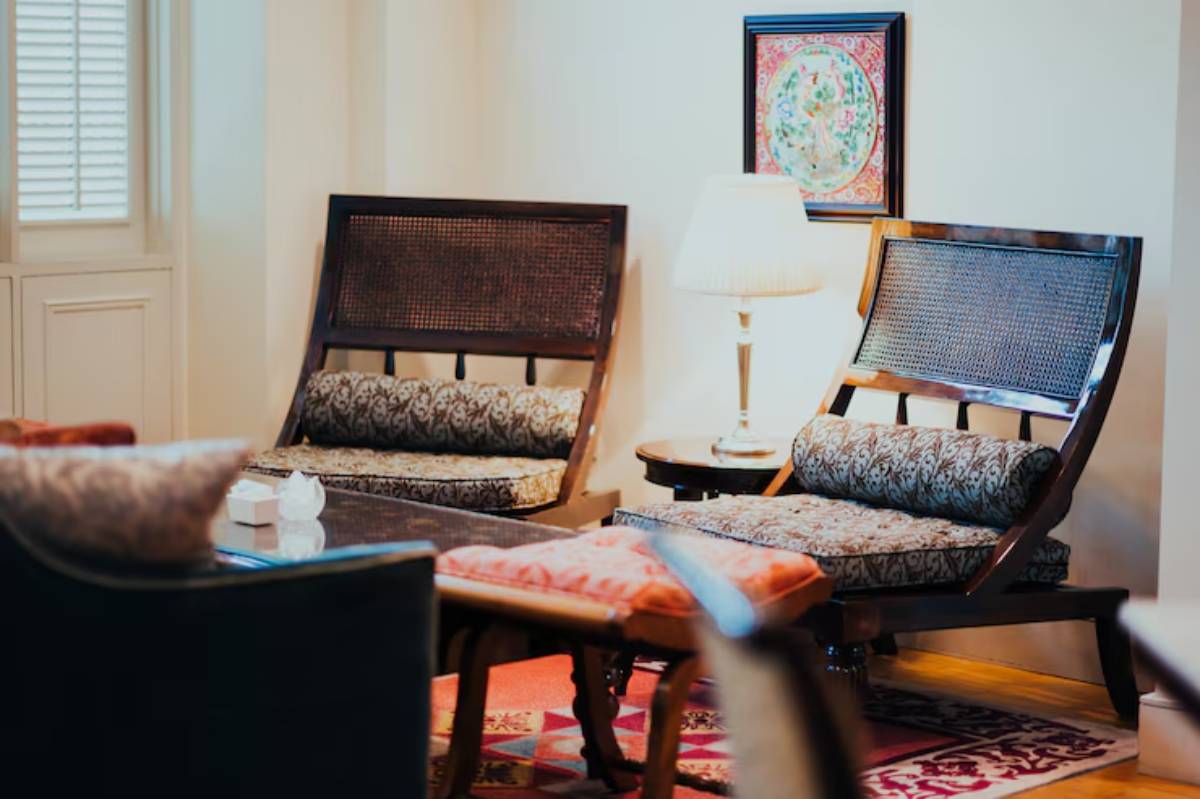 Cozy seating area featuring two elegant wooden chairs, a lamp, and a decorative wall art in a bright, inviting room.