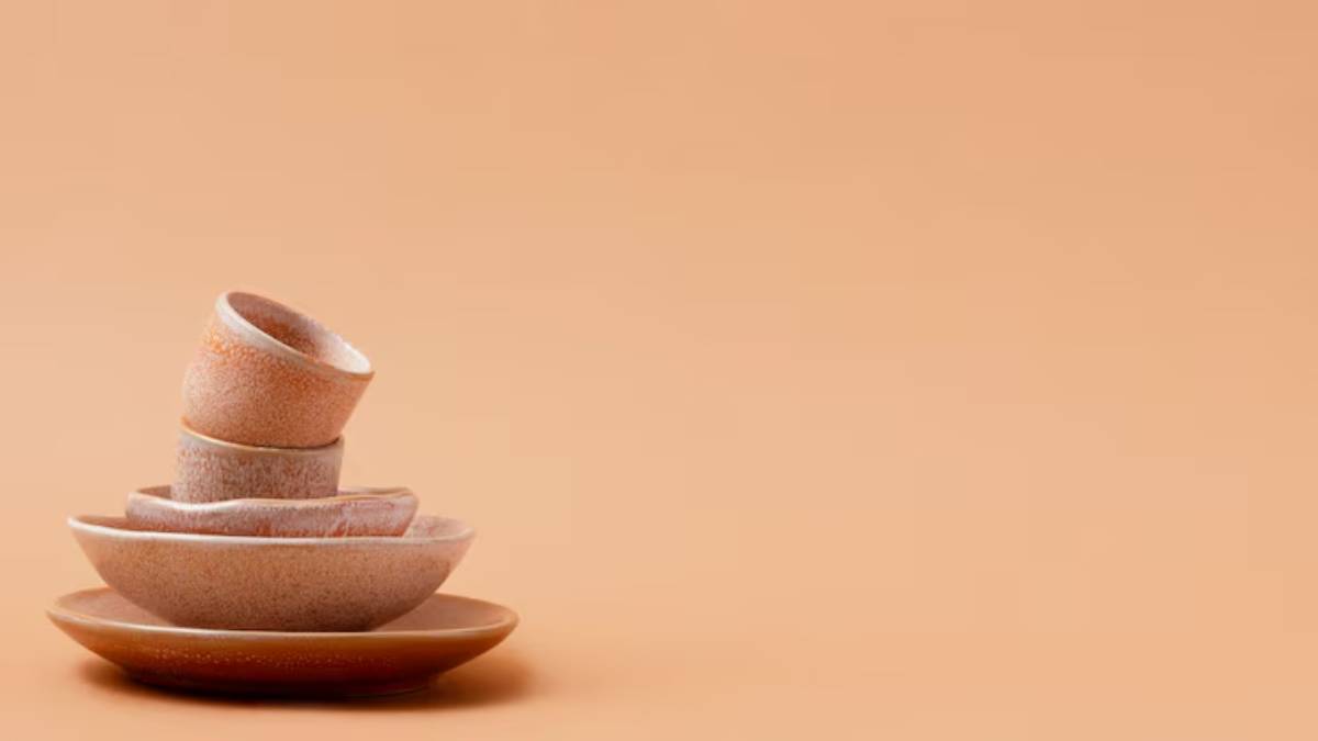 A stack of textured ceramic bowls and a plate, displayed against a warm, peach-colored background.