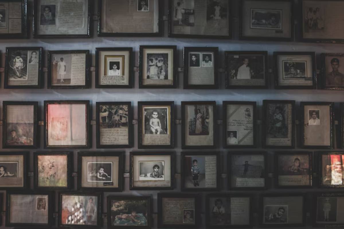 A collage of framed photographs with handwritten notes, showcasing portraits and memories hung on a wall.
