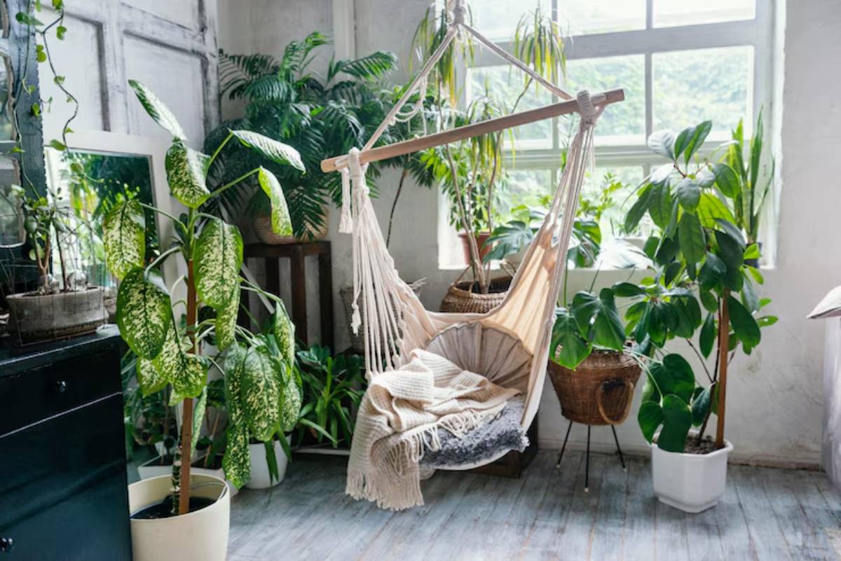 A cozy macramé hammock hangs in a sunlit room, surrounded by lush green plants and a mirror, creating a serene indoor oasis.