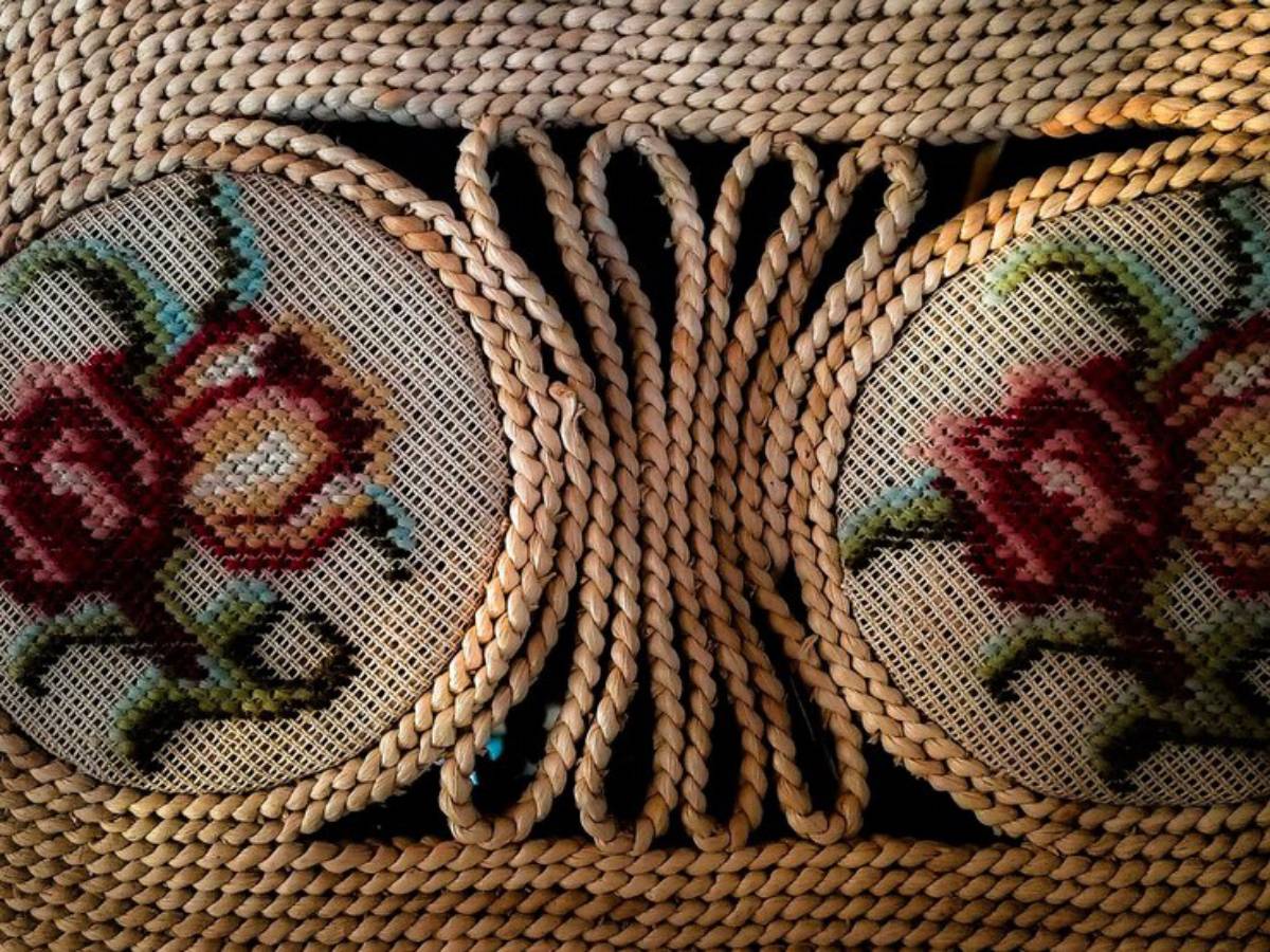 An intricate woven design featuring two circular, floral-patterned cushions with vibrant roses, complemented by braided accents.