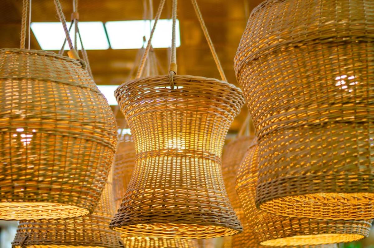 A collection of woven wicker pendant lights, softly illuminated, hanging against a warm, golden background.