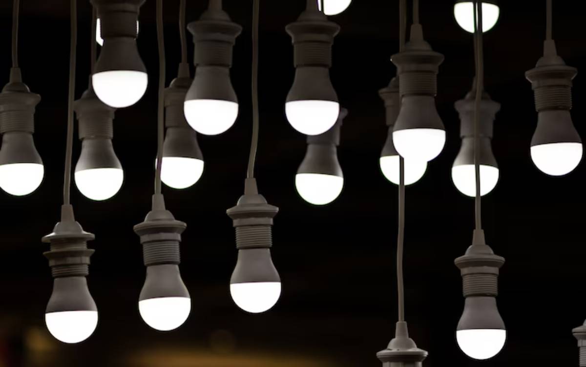 A cluster of hanging light bulbs with glowing white bulbs, creating a warm ambiance against a dark background.
