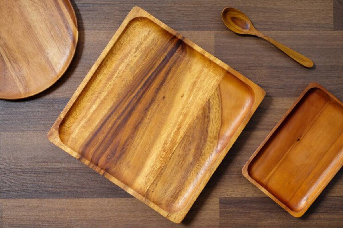 A vibrant collection of wooden serving trays and a spoon arranged on a dark wooden surface, showcasing natural textures.