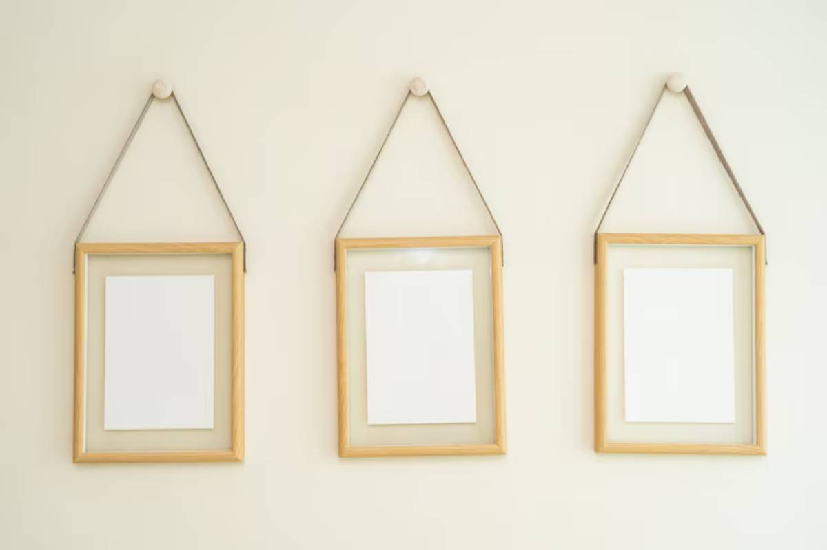 Three unframed wooden photo frames hanging on a light-colored wall, each displaying a blank white sheet.