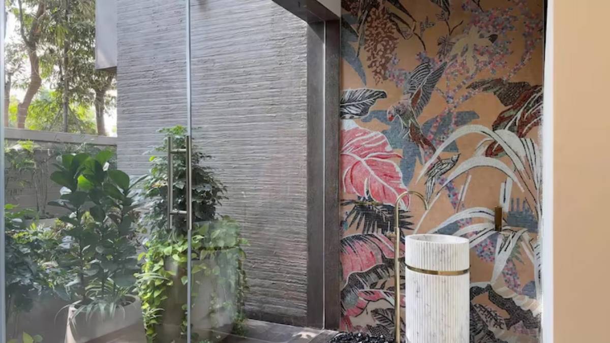A serene entryway featuring lush green plants, a stylish marble water feature, and a vibrant floral mural on the wall.