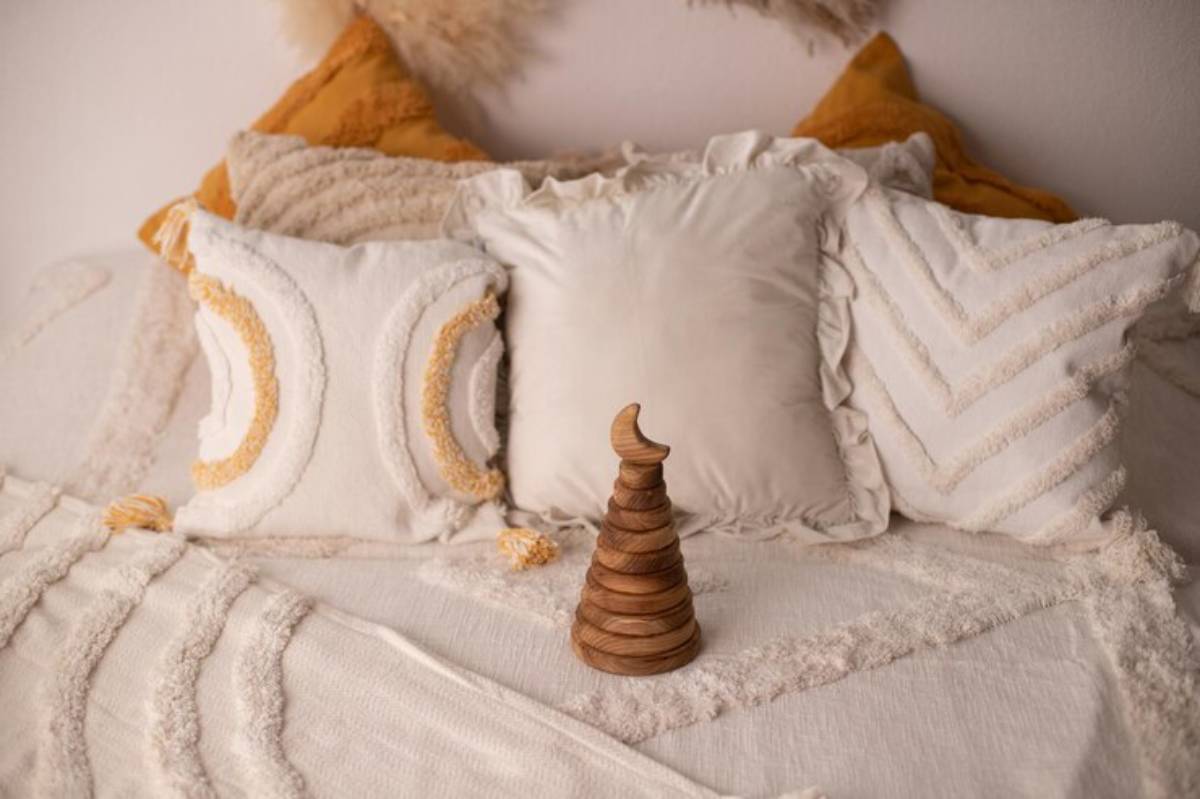A cozy arrangement of decorative pillows on a sofa, with a wooden stacking toy in the foreground, creating a warm, inviting atmosphere.